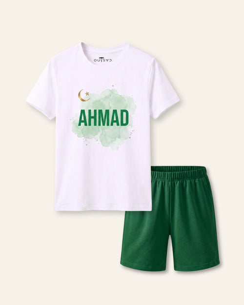 Kids white tee with a large name print under a crescent and green shorts