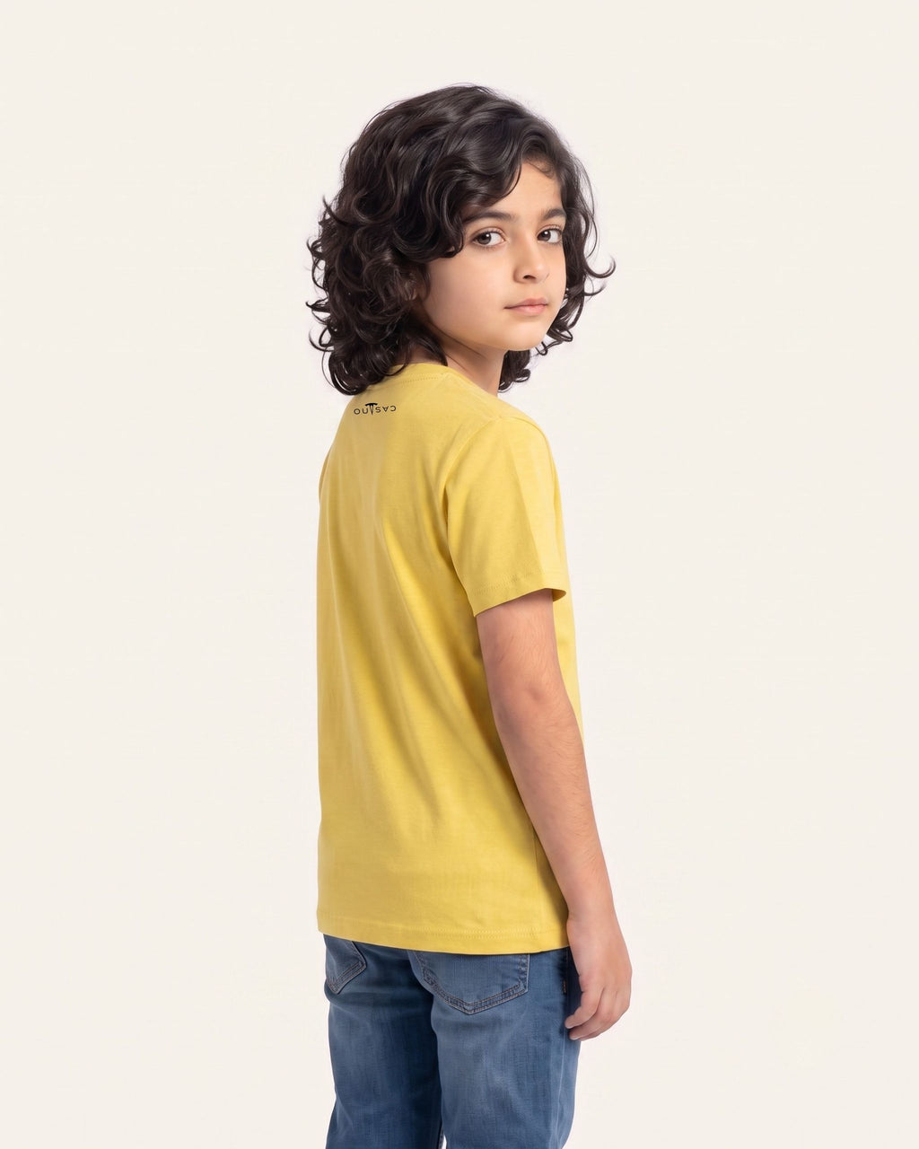 Boy wearing a yellow OUTCAST basic tee, side view