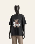 Woman wearing a black cotton tee with a teddy bear and BE LOVED wordmark print