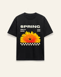 Front of the black cotton tee with a bright sunflower over a checkerboard strip and SPRING lettering