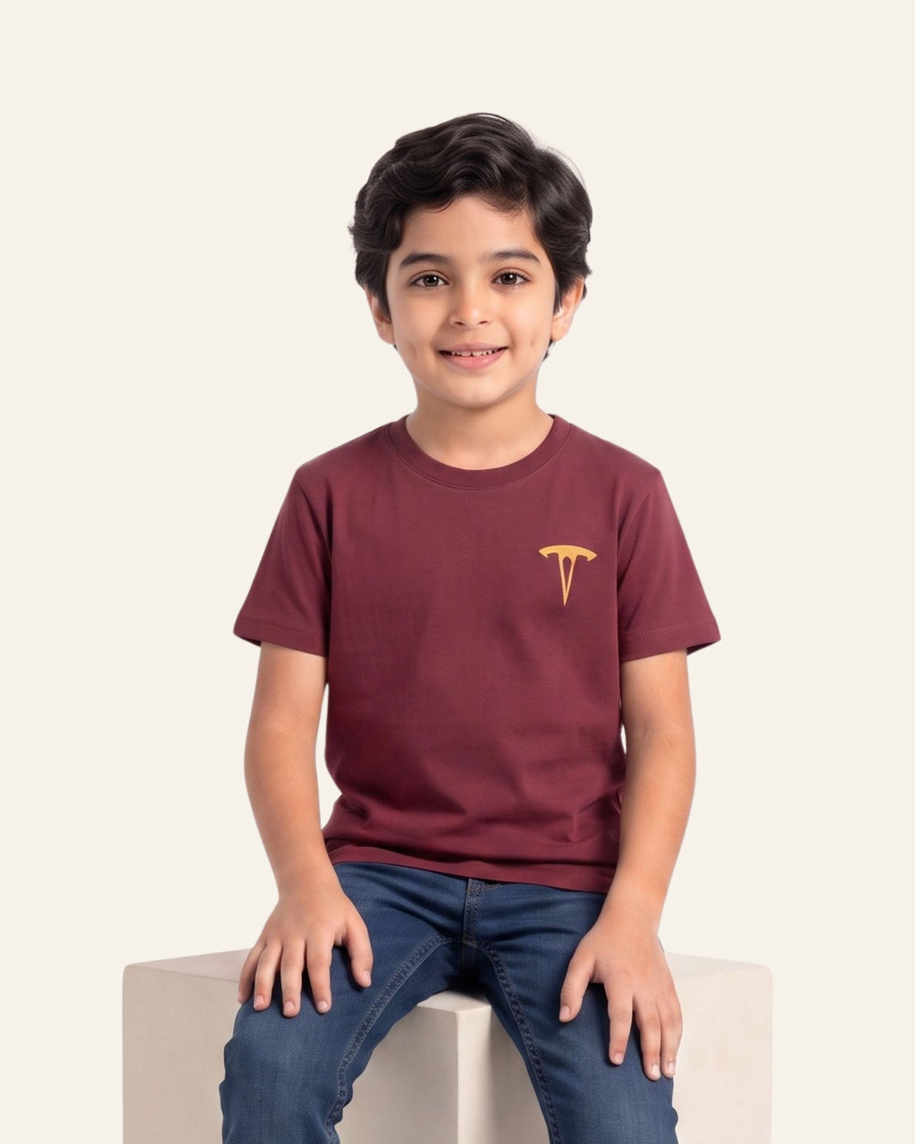 Boy sitting wearing a maroon OUTCAST basic tee with jeans