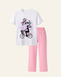 White kids tee with a girl cycling past a pink Eiffel Tower and matching pink trousers